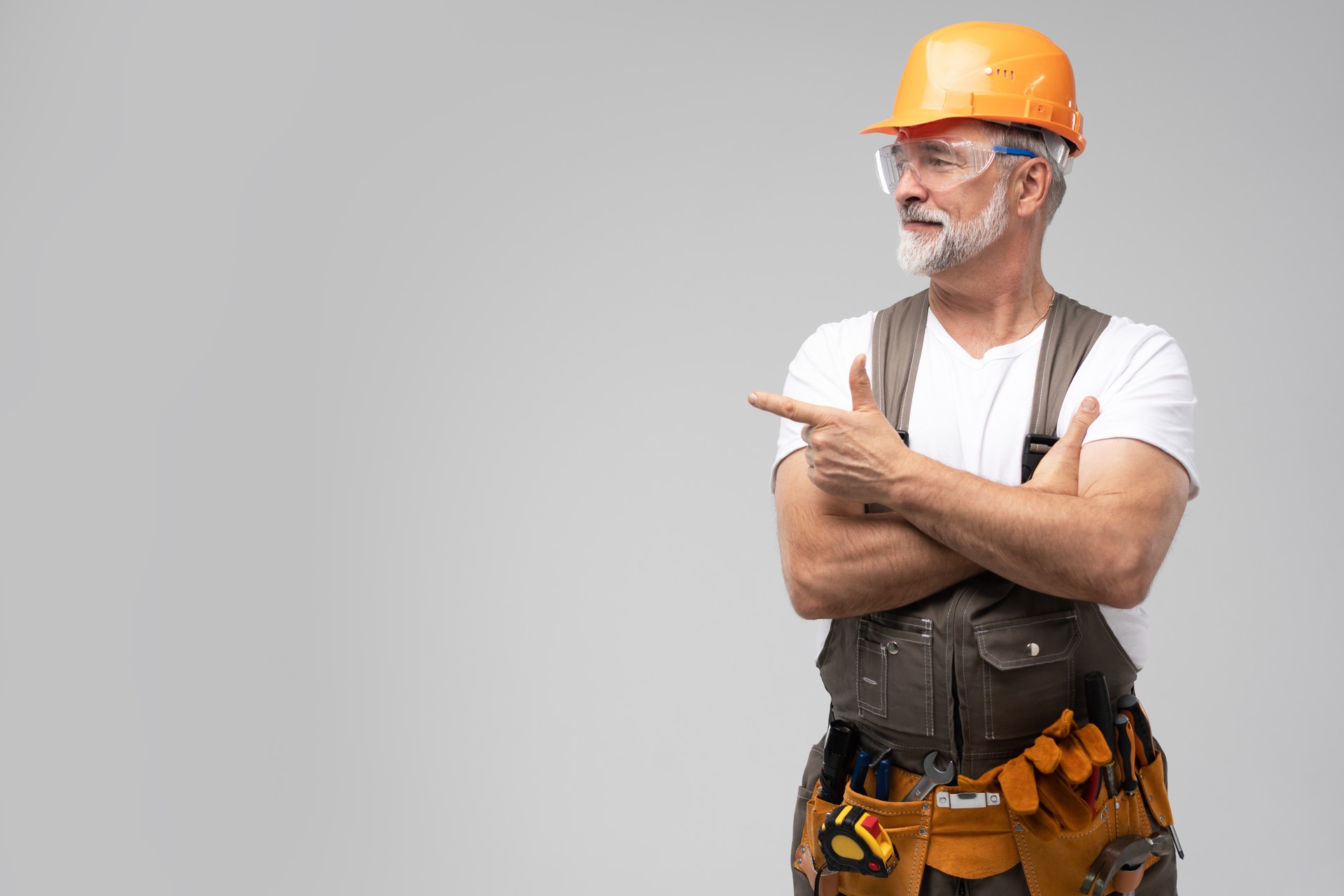 portrait of mature happy handyman presenting something isolated on white background.